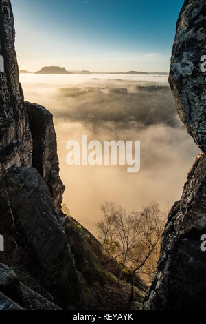 Landscape in the National Park Sächsische Schweiz with rock formations and fog in the river Elbe valley, seen from Bastei bridge at sunrise Stock Photo