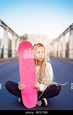 Young woman sitting on bridge with skate portrait Stock Photo