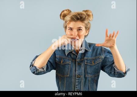 Young beautiful strongly emotional girl shows different gestures on an isolated blue background. Concept of human emotions Stock Photo