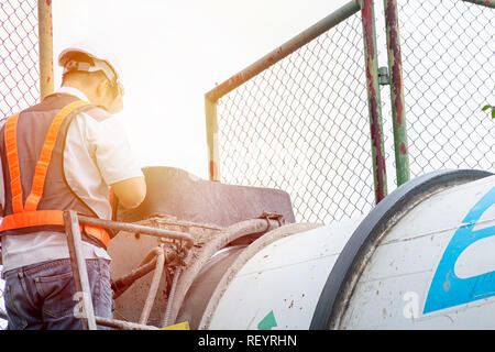 Engineers are reviewing a large cement mixer. Construction, Real Estate work requires specialists in care. Standing on the Mixing drum car. Stock Photo