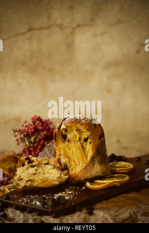 Italian Panettone on wooden board with warm background. Seasonal cake New Years celebration food. Stock Photo