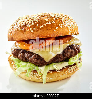 Studio shot close-up of a tasty hamburger with ground meat, tomatoes, cheese and salad in a sesame bun against white background for copy space Stock Photo