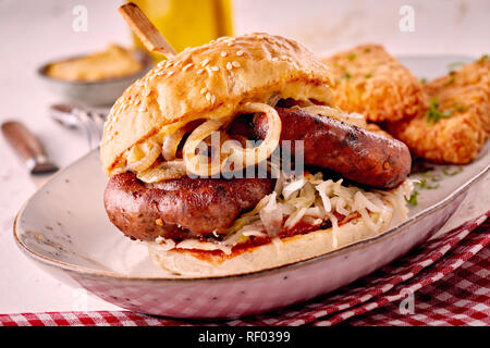 Grilled spicy bratwurst burger on a sesame bun with fried onion trimmings served in a dish with checked napkin for regional German cuisine Stock Photo