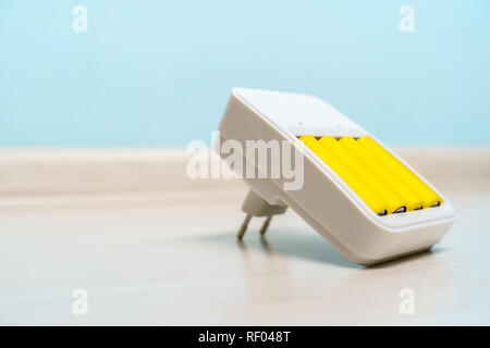 Picture of charger with two yellow batteries on empty blue background Stock Photo