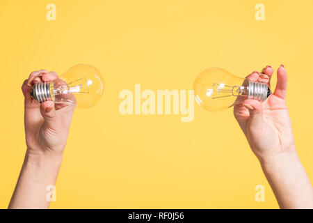 cropped view of female hands holding led lamps isolated on yellow, energy efficiency concept Stock Photo
