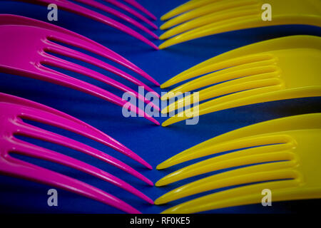 Yellow and pink cutlery plastic forks arranged on blue background. Color trends and plastic waste problem concept Stock Photo