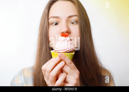funny young woman wants to eat pink cake Stock Photo