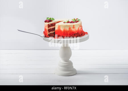 white cake decorated with currant and mint leaves on stand with spatula isolated on white Stock Photo