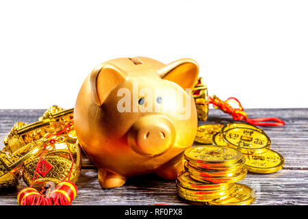 Piggy bank with golden coins and chinese ornament on the wooden table. Chinese New Year. Year of the earth pig Stock Photo
