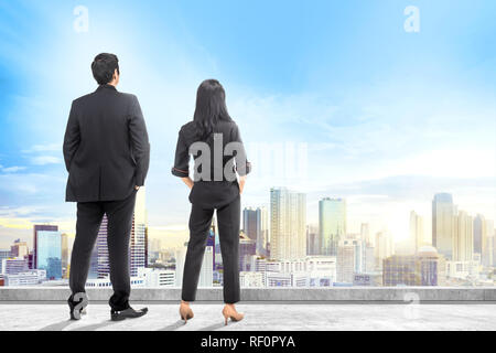 Rear view of asian business people looking at cityscapes from rooftop of building Stock Photo