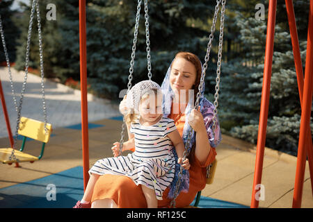 Russian Orthodox woman riding on a swing with a little daughter Stock Photo