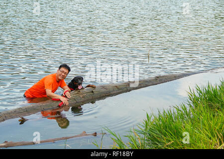 Man and dog having fun in the lake Stock Photo