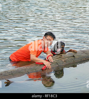Man and dog having fun in the lake Stock Photo