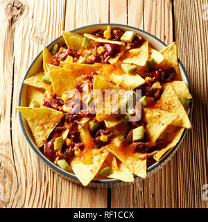 Dish of Mexican chili con carne with nachos au gratin viewed from overhead on rustic wood in square format for a menu Stock Photo