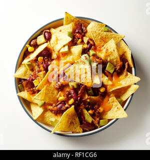 Mexican chili con carne with nachos topped with cheese and baked in an oven viewed from overhead in a dish over white Stock Photo