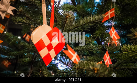 Traditional and typical Christmas Danish decoration made of paper woven heart or julehjerte with Danish flags on Christmas green pine tree Stock Photo