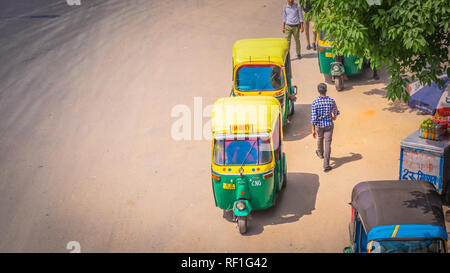New Delhi / India - April 14 2017: Yellow auto rickshaws on a busy and polluted highway / motorway in New Delhi called the Outer Ring with many cars Stock Photo