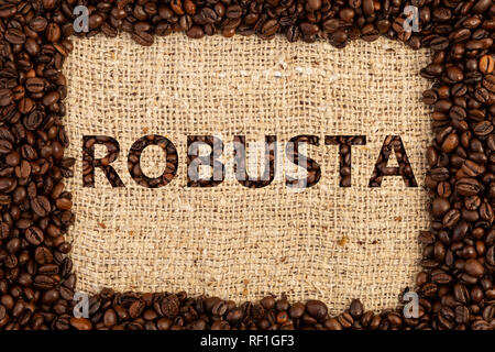 Robusta coffee type spelled inside frame made out of scattered beans on brown textured background Stock Photo