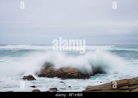 Waves crash against a rocky shore in the soft morning lifht. Stock Photo