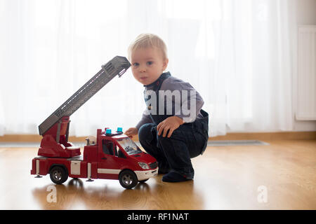 Little toddler boy, playing with fire truck car toy at home Stock Photo