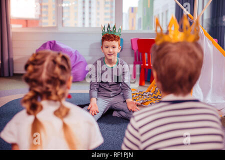 Cheerful little male person looking at his friends Stock Photo