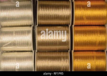 Cutout texture closeup on coils of colored sewing threads white,gold and yellow. Stock Photo