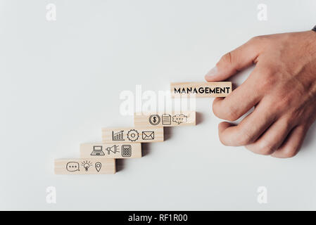 cropped view of man holding wooden block with word 'management' on top of wooden bricks with icons isolated on white Stock Photo