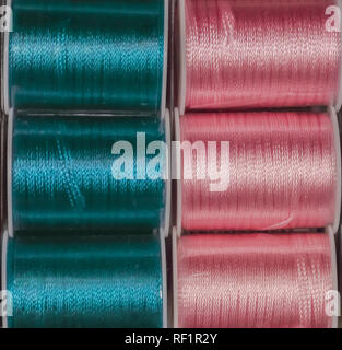 Cutout texture closeup on coils of colored sewing threads blue and pink. Stock Photo