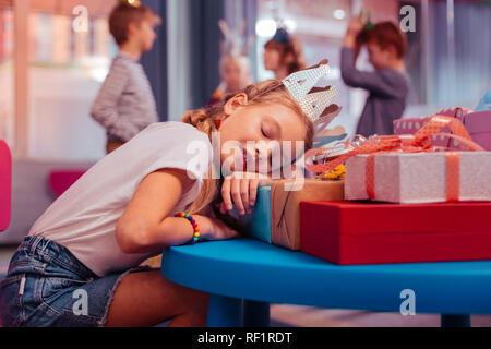 Exhausted birthday girl leaning on her presents Stock Photo