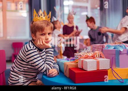 Bored blonde boy leaning elbows on table Stock Photo