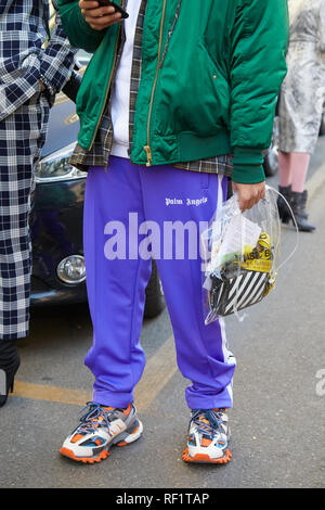 MILAN, ITALY - JANUARY 13, 2019: Man with purple Palm Angels trousers, green bomber jacket and transparent bag before John Richmond fashion show, Mila Stock Photo