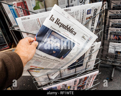 PARIS, FRANCE - JUNE 13, 2018: Man buying La Repubblica newspaper at press kiosk showing on cover  U.S. President Donald Trump meeting North Korean leader Kim Jong-un in Singapore   Stock Photo