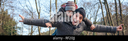 Man giving piggyback ride to happy kid in the forest Stock Photo