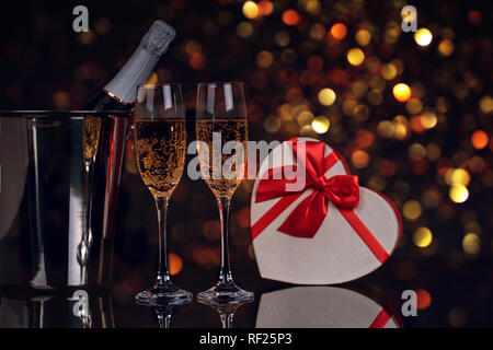 Champagne bottle in bucket with two wine glasses and gift box on black background. Love, Valentines day concept Stock Photo