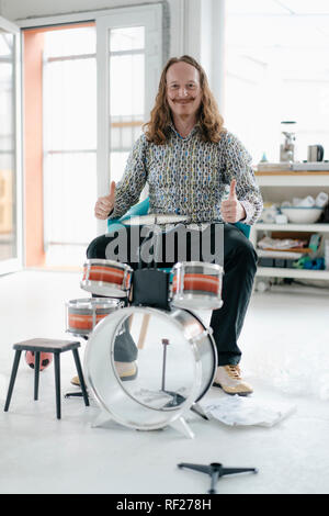 Portrait of confident man sitting at toy drums Stock Photo