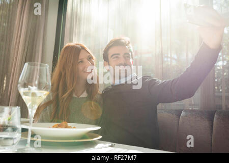 Smiling couple taking a selfie in a restaurant Stock Photo