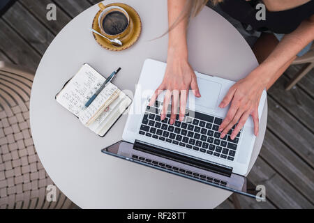 Young woman sitting outdoors working on laptop, top view Stock Photo