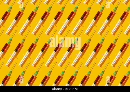 Multiple syringes organized in a pattern over yellow background Stock Photo
