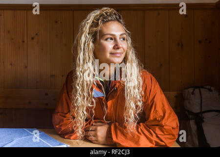 Young woman sitting in mountain hut, taking a break from hiking Stock Photo