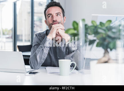 Businessman sitting in office, thinking Stock Photo
