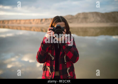 Young woman taking picture with camera on the beach Stock Photo