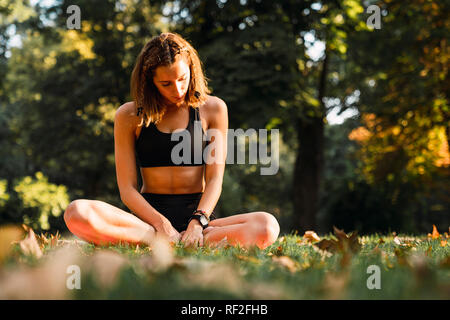 Fit young woman practicing yoga in a park Stock Photo
