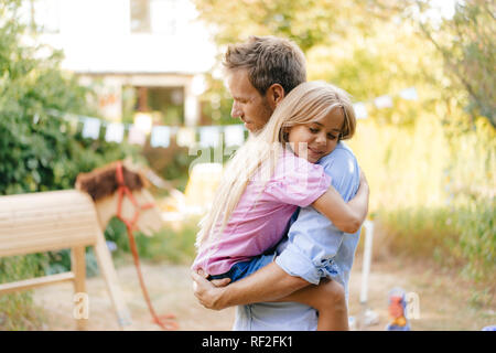 Father cuddling with daughter in garden Stock Photo