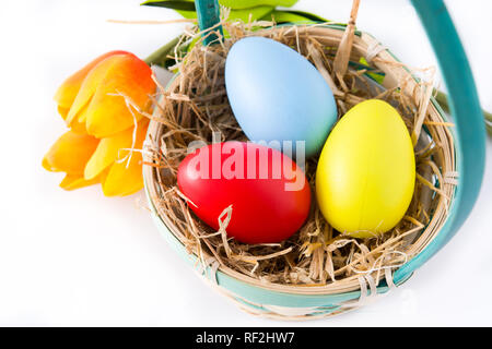 Colorful easter eggs in a basket and tulips isolated on white background. Stock Photo