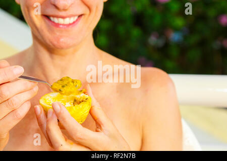 Woman eating passion fruit (Passiflora edulis). Stock Photo