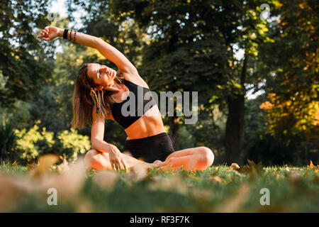 Fit young woman practicing yoga in a park Stock Photo