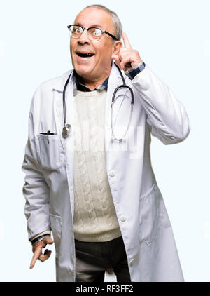 Handsome senior doctor man wearing medical coat pointing finger up with successful idea. Exited and happy. Number one. Stock Photo