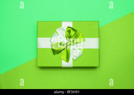 Real box with white and green bow and ribbon top view on Valentine's day isolated on green background. Flat lay. Copy space. Stock Photo