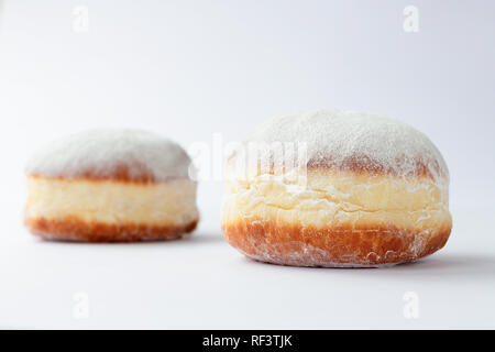 Two freshly made doughnuts filled with jam and covered in powdered sugar on a white background Stock Photo
