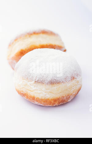Two freshly made doughnuts filled with jam and covered in powdered sugar on a white background Stock Photo